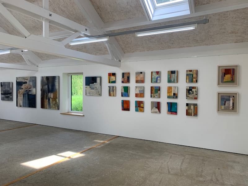 Print room exhibition space with high ceiling, wooden beams and window looking out onto green grass and art works displayed on white walls
